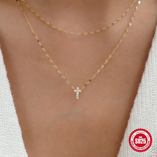 Gold necklace with a cross pendant on a person's neck, branded '925 Sterling Silver'.