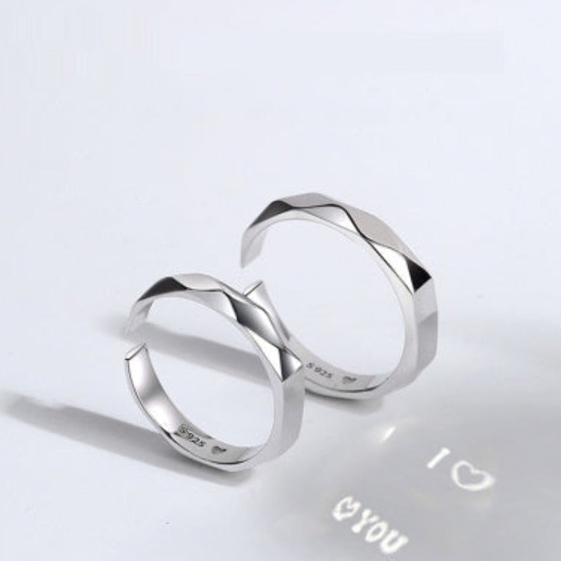 Two S925 Sterling Silver Light Reflection Rings by Jingqian with faceted surfaces are shown on a white background. The interior of the adjustable rings has inscriptions, and a projection below them displays "I â¤ YOU" with a heart symbol, capturing light reflections beautifully.